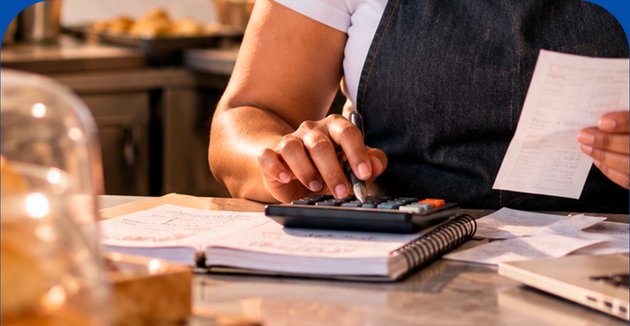 Mãos usando calculadora sobre documentos fiscais