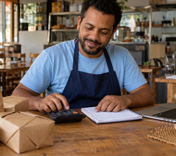 Empreendedor fazendo as contas do negócio com calculadora e caderno