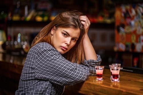 Mulher desconfortável em bar que não promove combate ao assédio